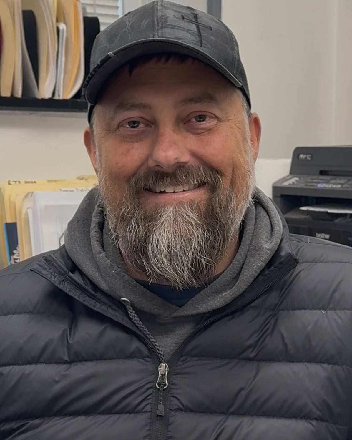 Man wearing a gray cap and black puffer jacket in an indoor setting